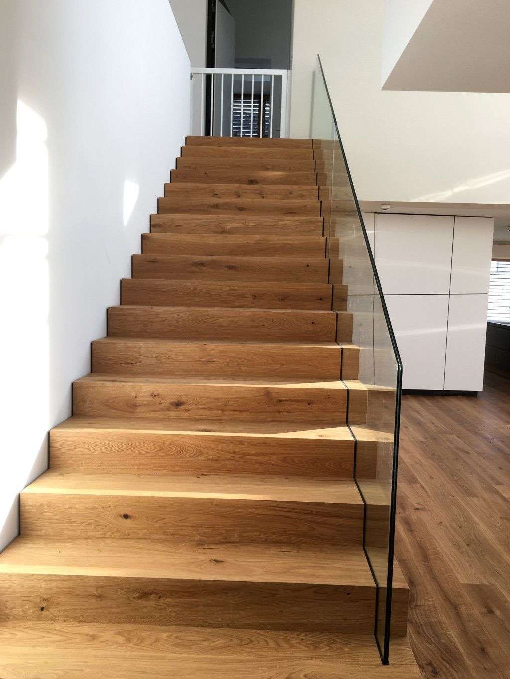 Moderne Treppe in Eiche mit Glasgeländer und Kindersicherheitsgeländer oben (Ulm)